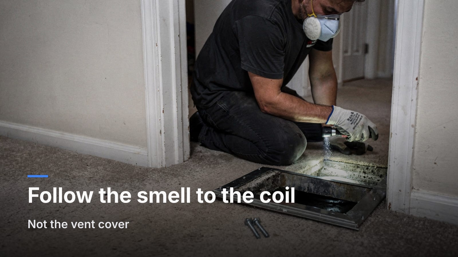 Homeowner shining a flashlight into an open floor register with the vent cover set aside on the carpet.